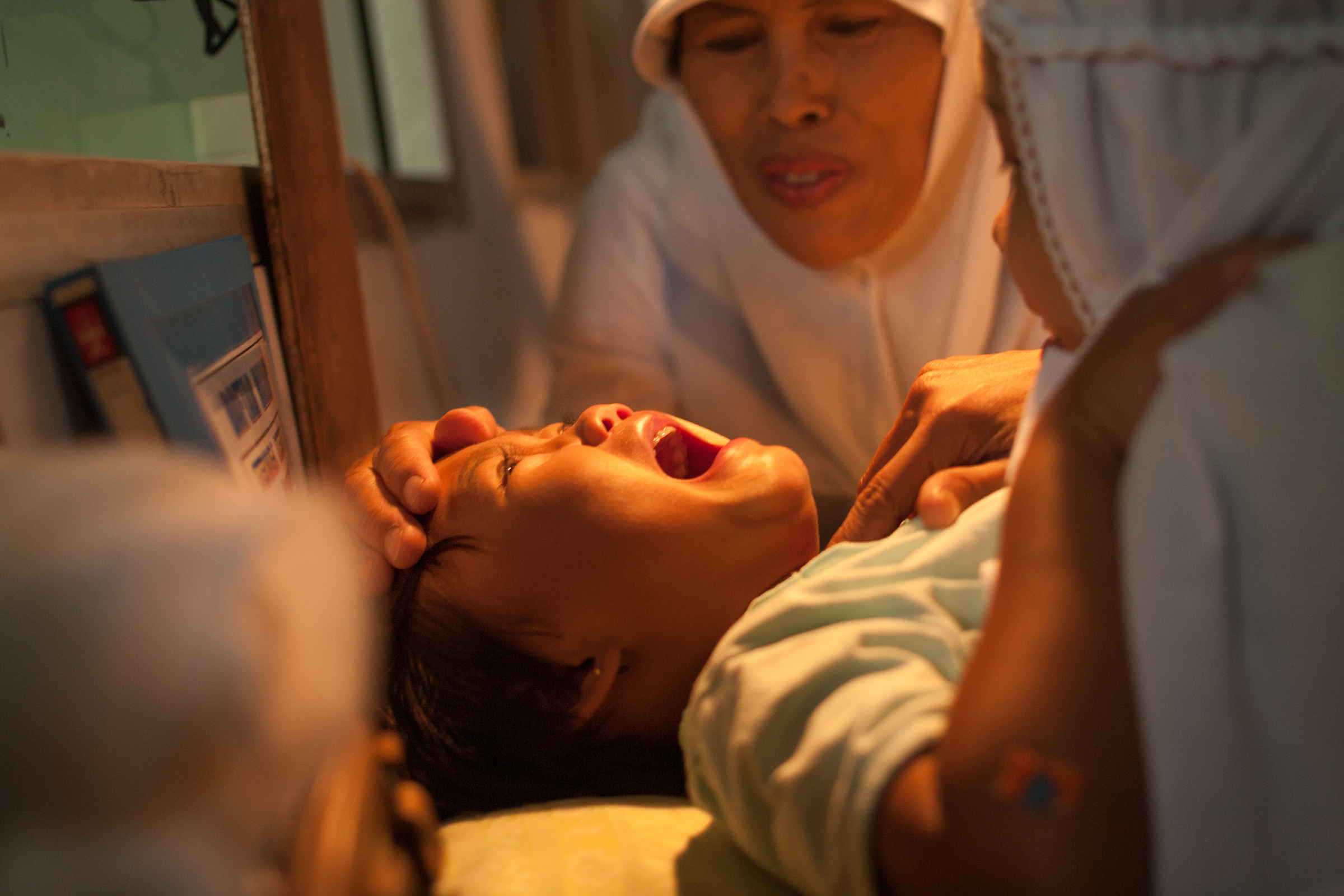 A young girl cries while being circumcised in Bandung, Indonesia.