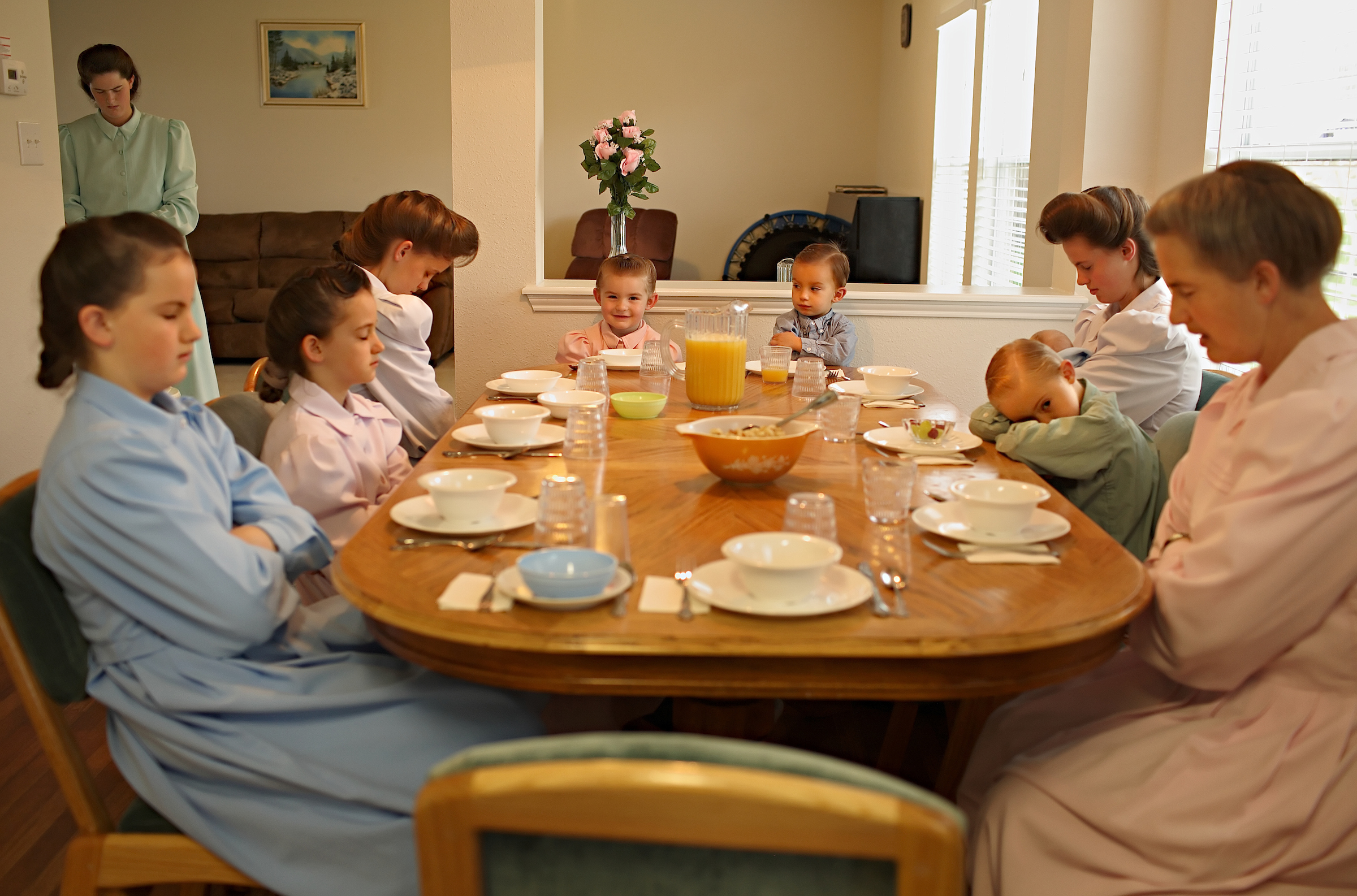 Sally Jeffs (far right) leads her family in prayer before breakfast at their temporary home, which housed many of the girls suspected of being in underage religious marriages.
